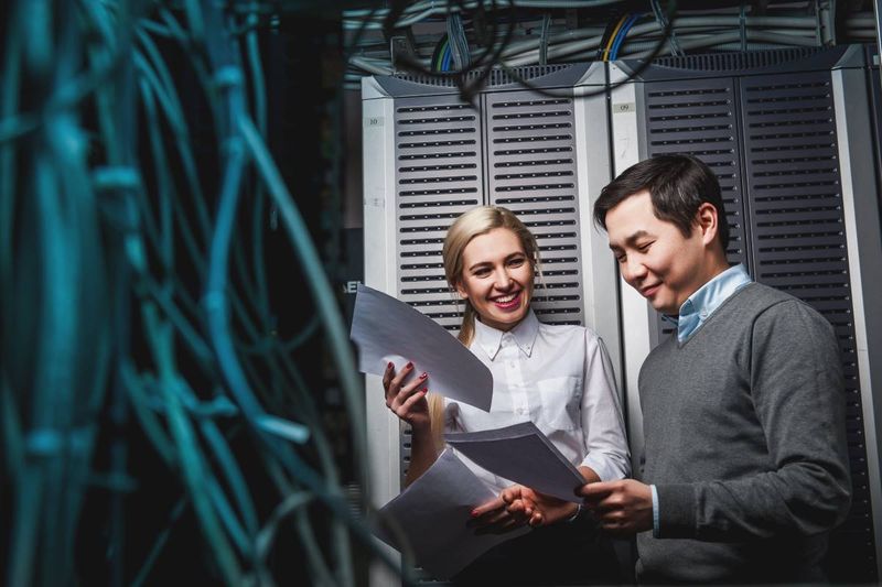 smiling tech workers in server room 