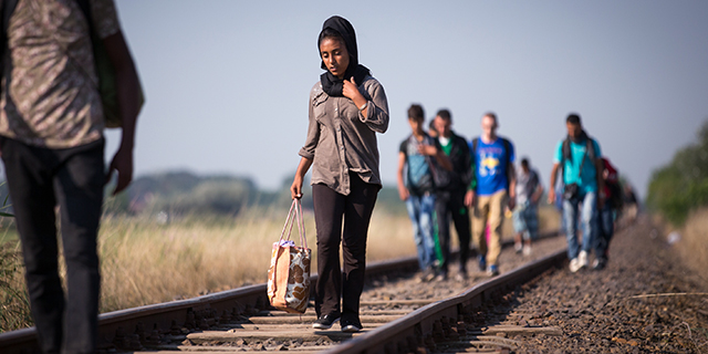 Migrants who have just crossed the border from Serbia into Hungary walk along a railway track on August 28, 2015 near Szeged, Hungary. Photo by Matt Cardy/Getty Images